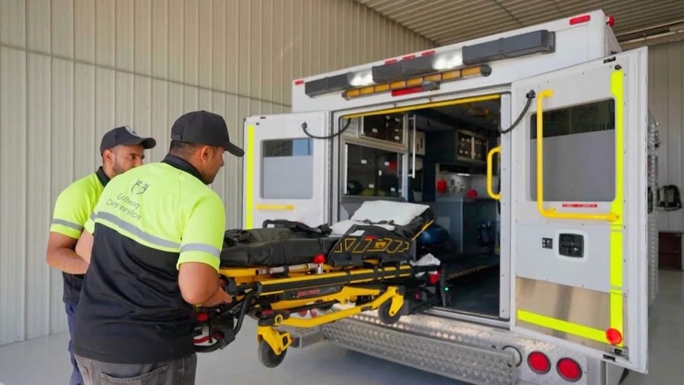 Gullwing Care attendants preparing a stretcher at the rear of a transport vehicle