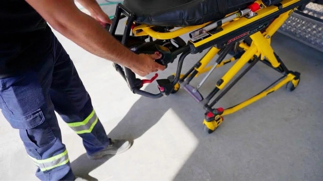 A transport attendant handling the powered stretcher equipment