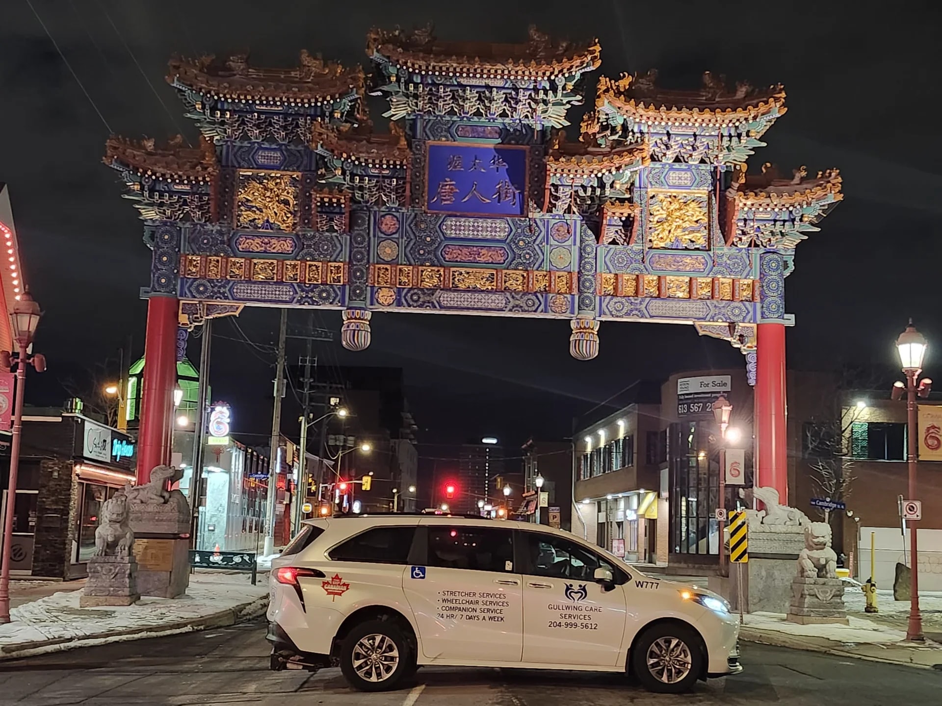 Gullwing Care minivan near an illuminated Chinatown gateway