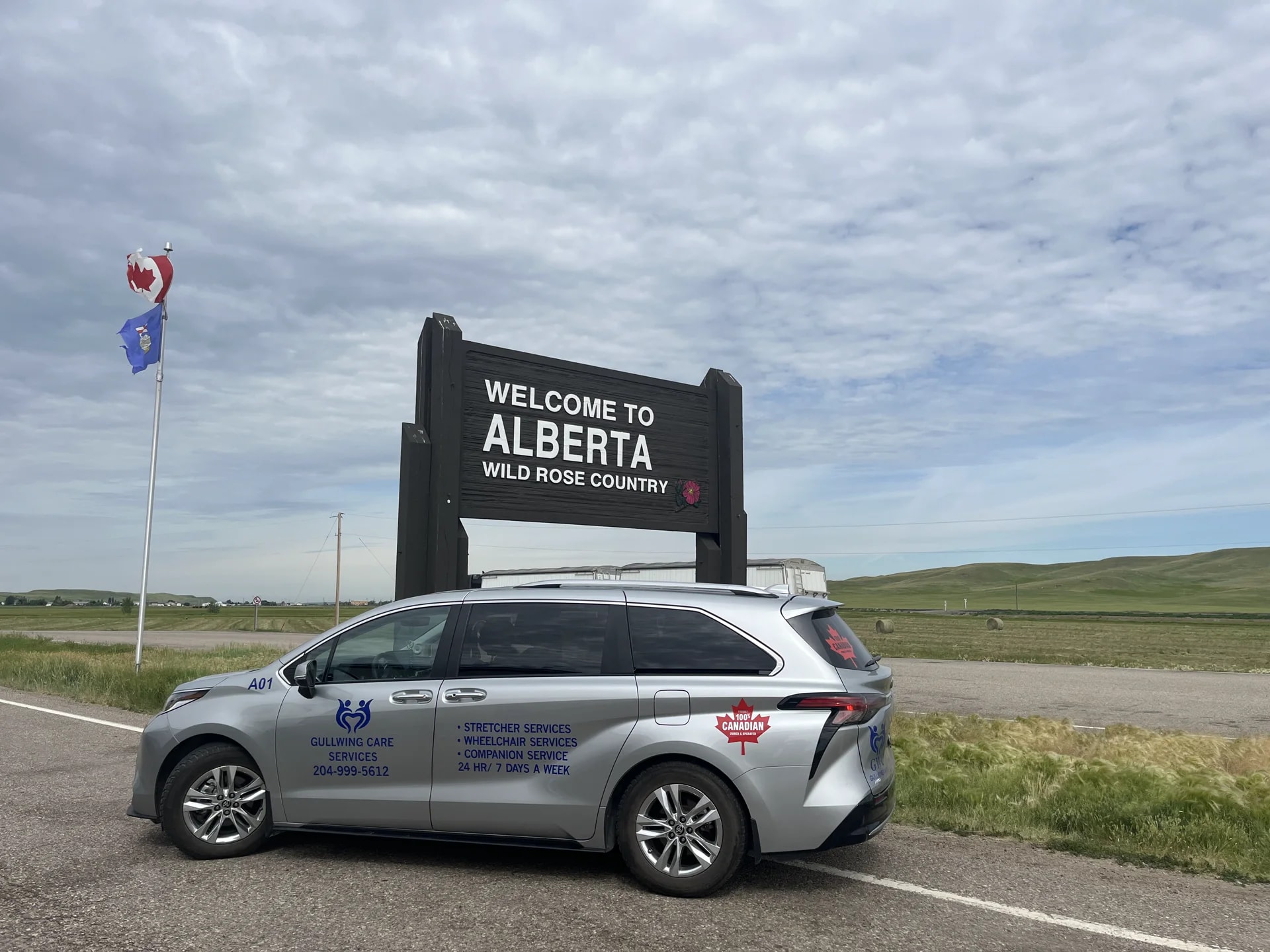 Gullwing Care minivan at the Welcome to Alberta sign